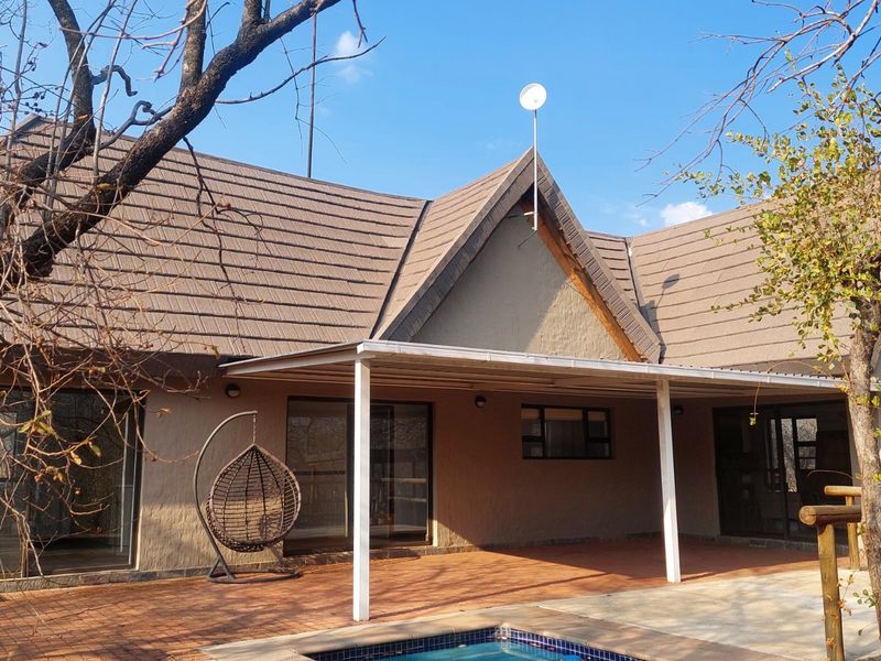 Rear view of the house featuring a covered patio area, swimming pool, and tiled roof structure.