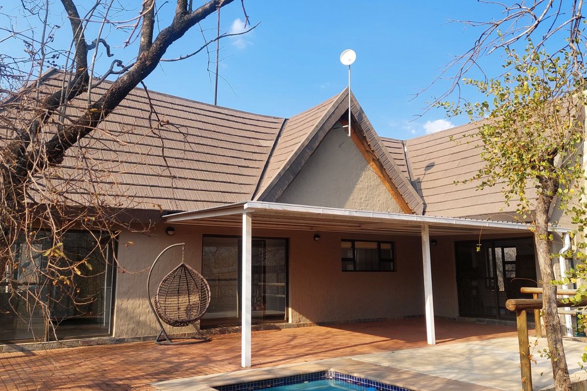 Rear view of the house featuring a covered patio area, swimming pool, and tiled roof structure.