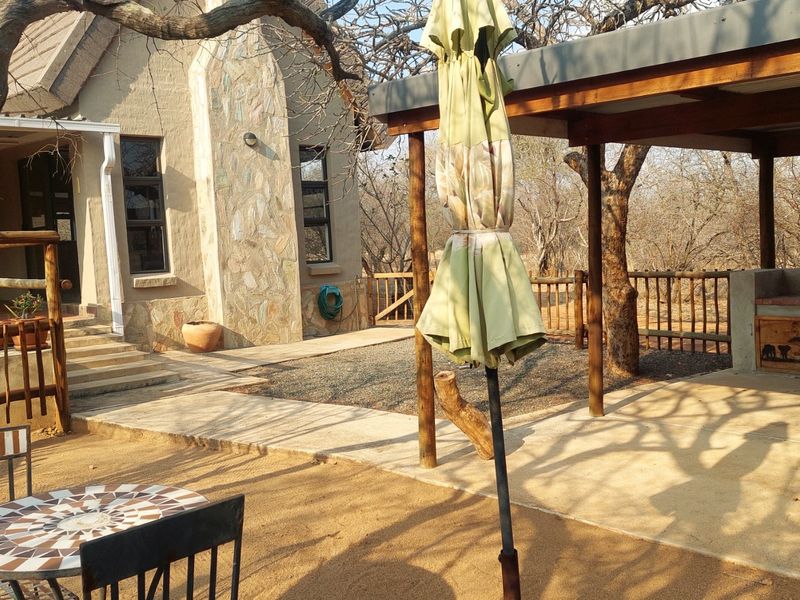 Outdoor entertainment area featuring a covered patio with a built-in braai, stone-clad exterior wall, and timber pergola structure.