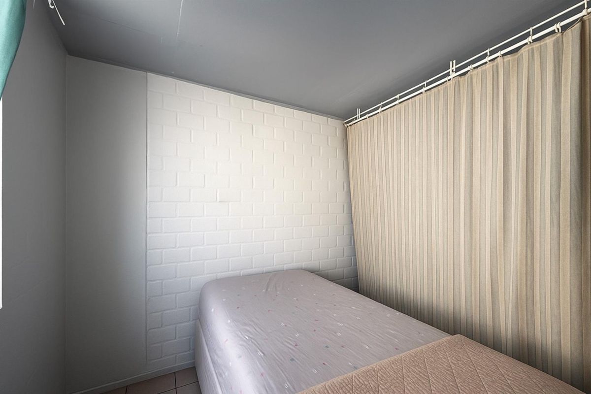 A bedroom featuring a white brick accent wall and a ceiling-mounted curtain track.
