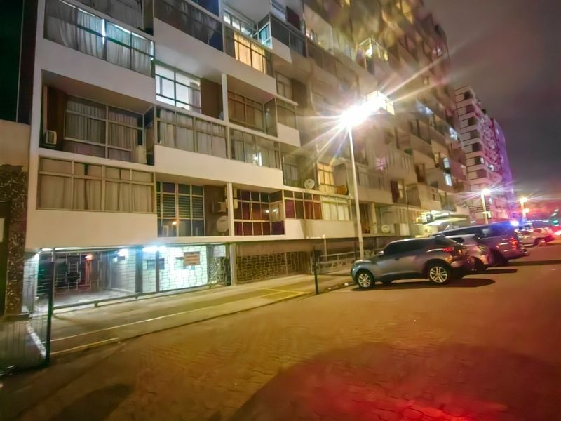 Night view of the apartment building facade featuring multiple balconies and ground-level parking access.