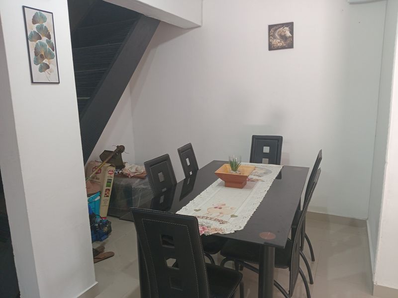 A dining area featuring a staircase leading to an upper level, with neutral wall finishes and tiled flooring.