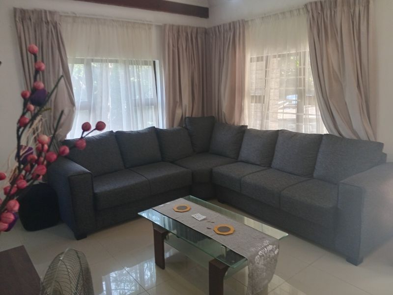 A comfortable living room featuring tiled flooring and large windows with curtain treatments, providing a bright and functional space for relaxation.