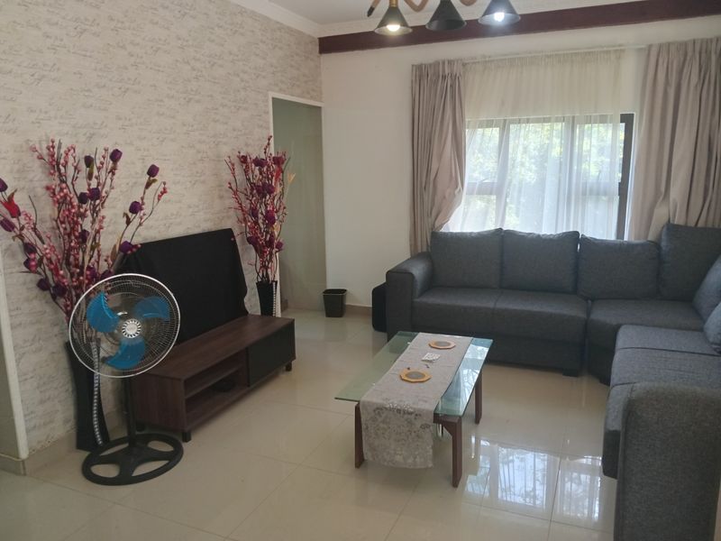 A comfortable living room featuring tiled flooring, neutral wall finishes, and large windows that allow for natural light.