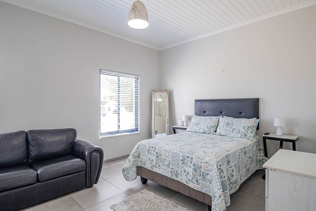 A well-maintained bedroom featuring tiled flooring, a tongue and groove ceiling, and venetian blinds, offering a clean and functional living space.