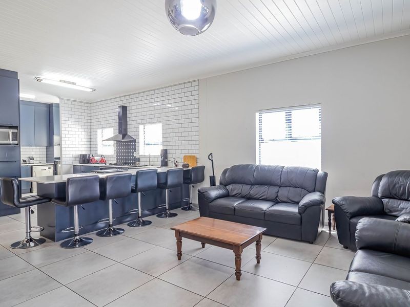 Spacious open-plan living area featuring a modern kitchen with a large island, subway tile backsplash, and neutral tiled flooring throughout.