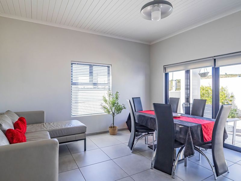 Bright open-plan living and dining area featuring tiled floors, tongue and groove ceiling, and large sliding doors providing seamless access to the outdoor patio.