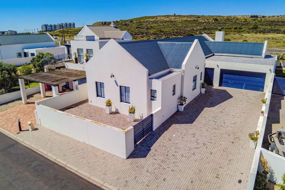 Aerial view of a modern residential property featuring a paved driveway, double garage, and a well-maintained exterior with a metal roof.