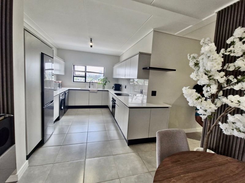 Modern kitchen featuring sleek built-in cabinetry, stone countertops, integrated appliances, and large format floor tiles in a clean, contemporary layout.