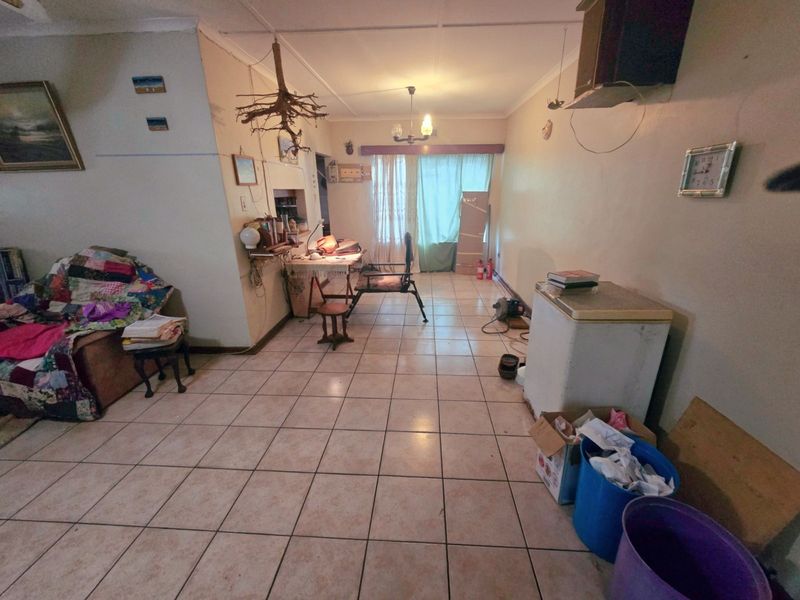 A living area featuring ceramic floor tiles and a sliding glass door leading to the exterior, offering a blank canvas for renovation.