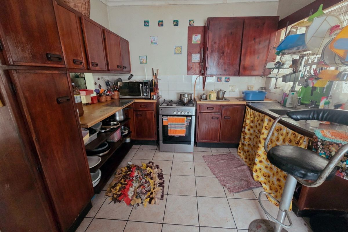 A dated kitchen featuring traditional wooden cabinetry, a gas stove, and tiled flooring, offering potential for a modern renovation.