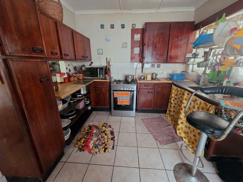 A dated kitchen featuring traditional wooden cabinetry, a gas stove, and tiled flooring, offering potential for a modern renovation.