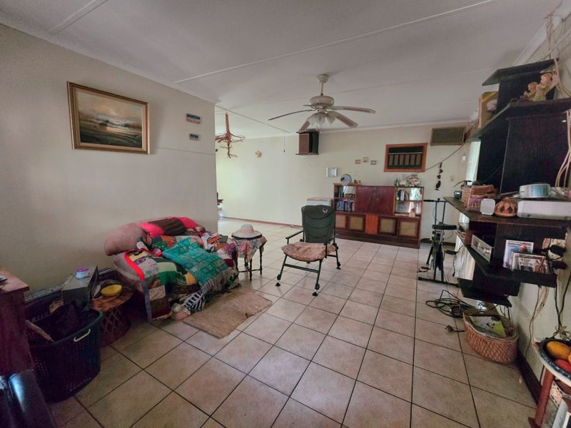 Spacious living area featuring tiled flooring, a ceiling fan, and an integrated air conditioning unit, offering a functional layout for comfortable family living.