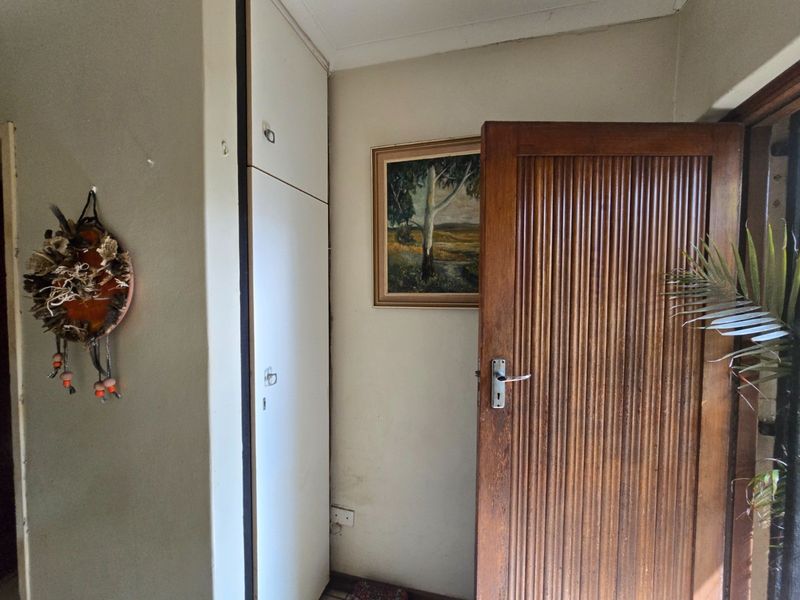 A functional hallway area featuring a built-in storage cupboard and a solid timber door with classic detailing.