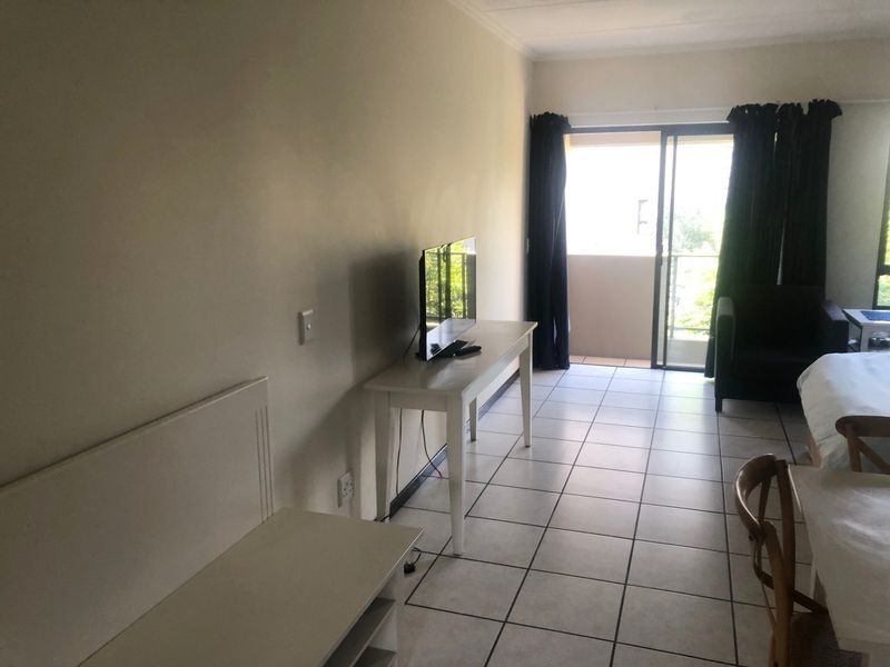A living area featuring tiled flooring and a sliding glass door providing access to an outdoor balcony space.