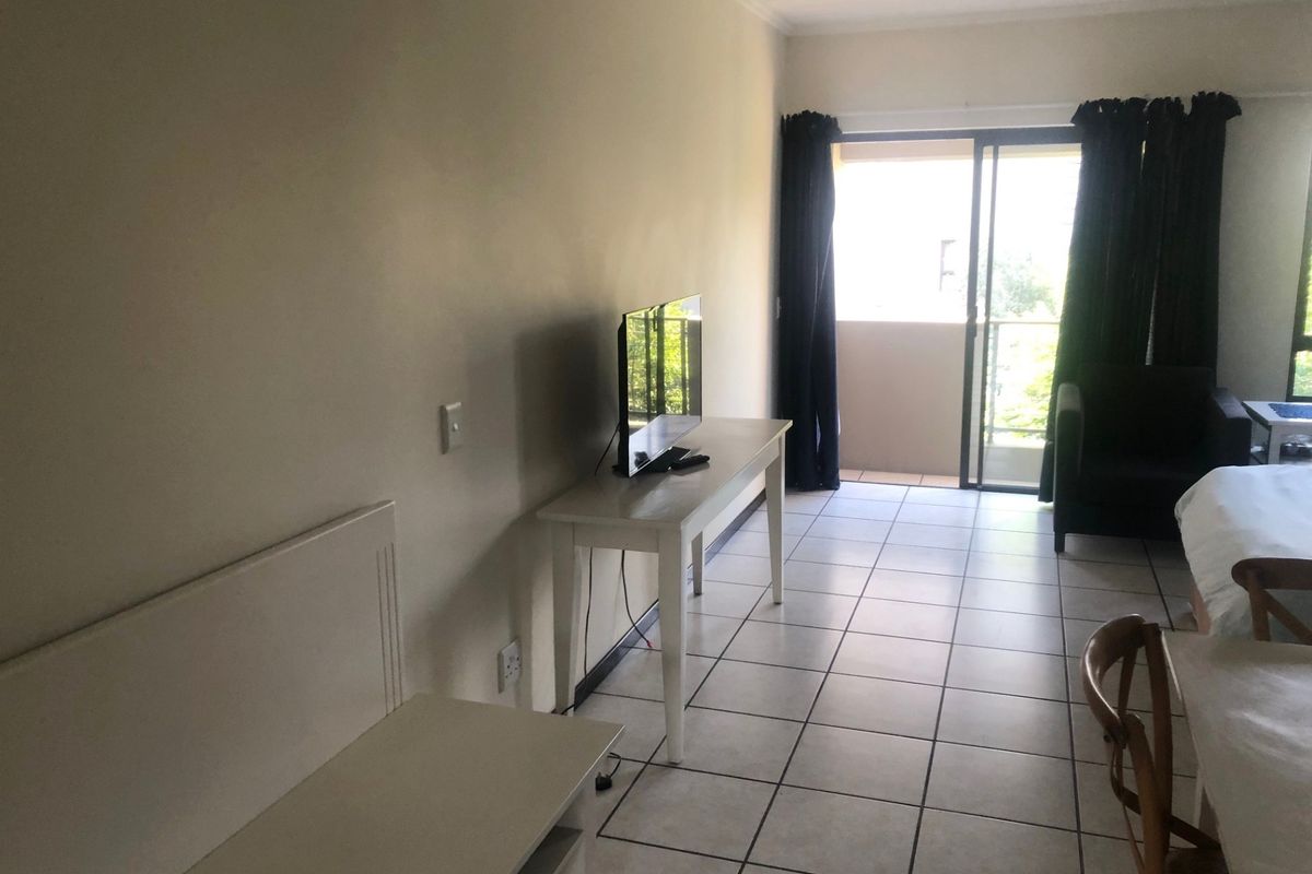 A living area featuring tiled flooring and a sliding glass door providing access to an outdoor balcony space.