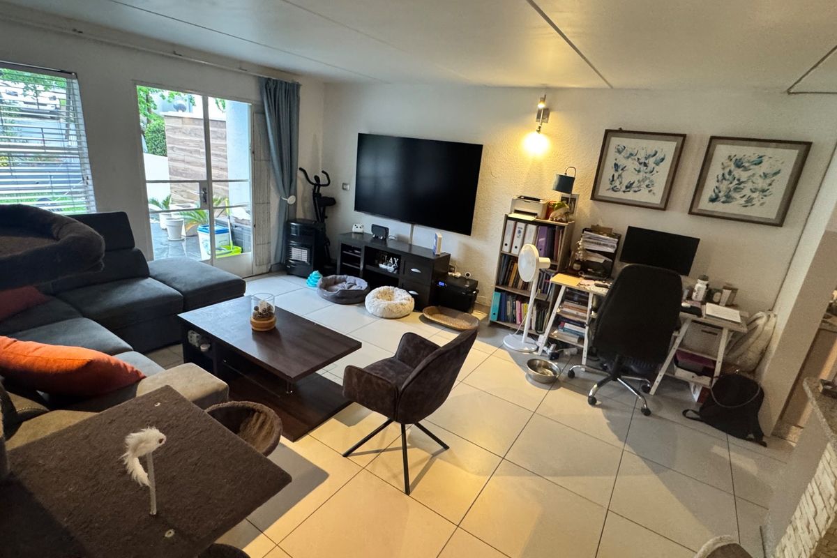 Spacious living room featuring large format floor tiles and a sliding glass door providing access to the outdoor area.