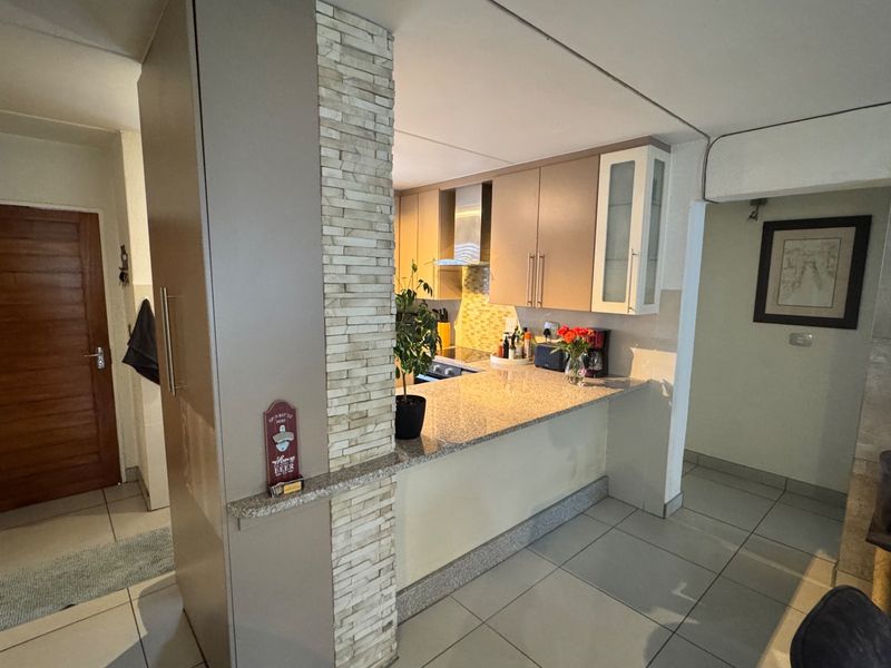 A functional kitchen featuring granite countertops, built-in cabinetry, and a decorative stone veneer pillar, seamlessly integrated into the open-plan living space.
