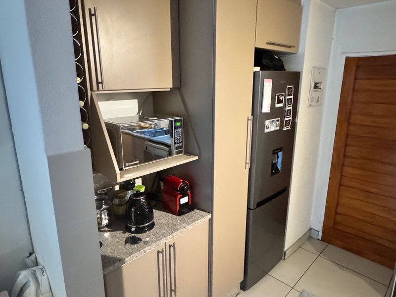 A compact kitchen area featuring modern built-in cabinetry, granite countertops, and tiled flooring, providing efficient storage and preparation space.