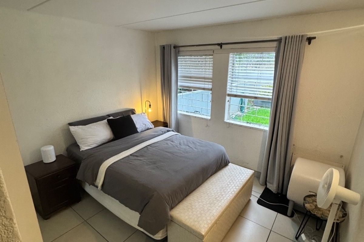 A functional bedroom featuring tiled flooring and window blinds, providing a neutral base for personal styling.