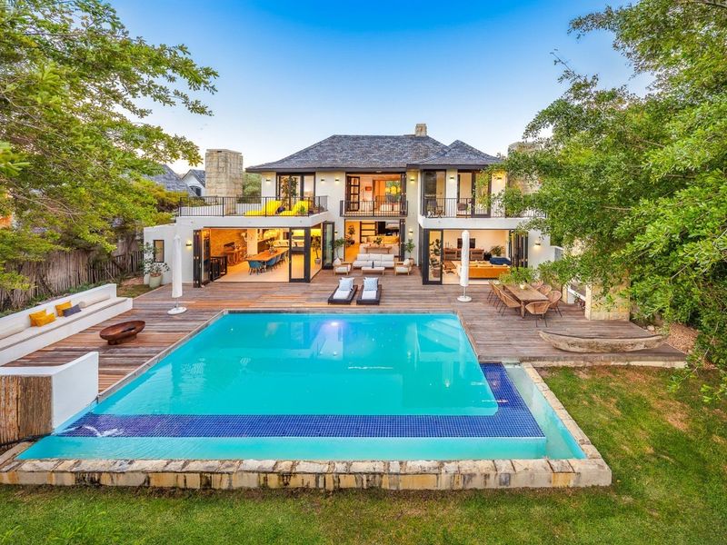 Stunning rear elevation featuring a large swimming pool, expansive timber decking, and seamless indoor-outdoor flow through bi-fold doors to the living areas.