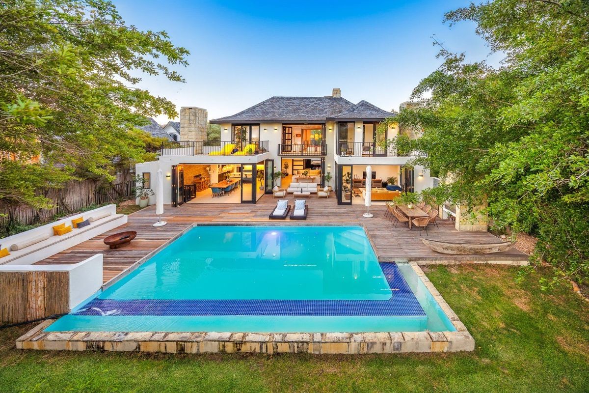 Stunning rear elevation featuring a large swimming pool, expansive timber decking, and seamless indoor-outdoor flow through bi-fold doors to the living areas.