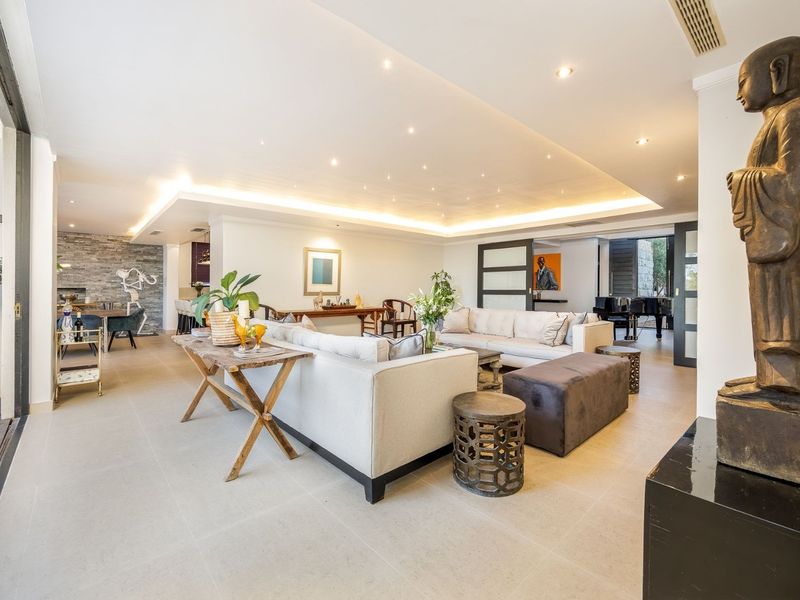 Spacious open-plan living area featuring large format floor tiles, recessed ceiling lighting, and a stone feature wall, creating a modern and elegant atmosphere.