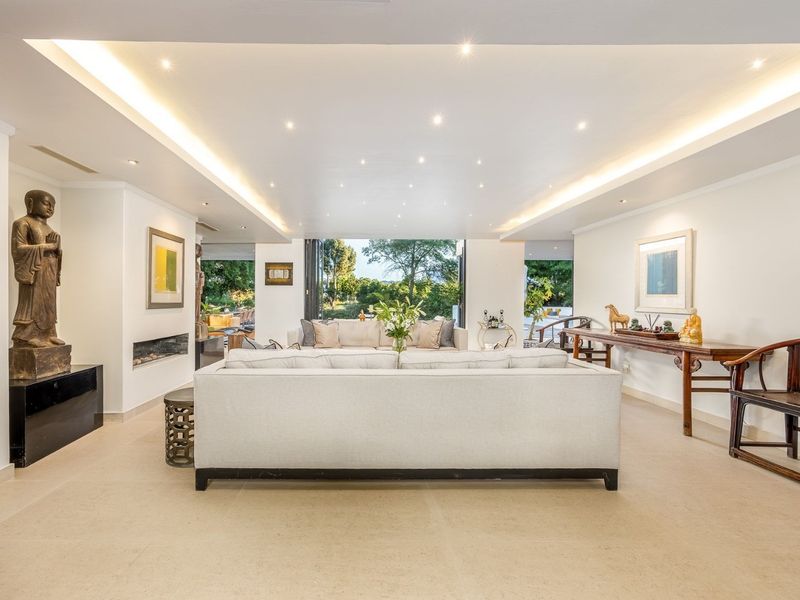 Spacious living room featuring recessed and cove lighting, a built-in fireplace, and large bi-fold doors opening to the garden.