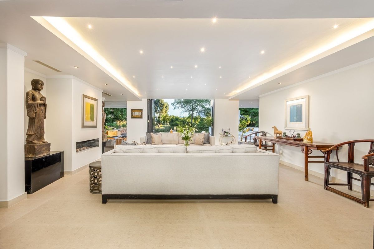 Spacious living room featuring recessed and cove lighting, a built-in fireplace, and large bi-fold doors opening to the garden.