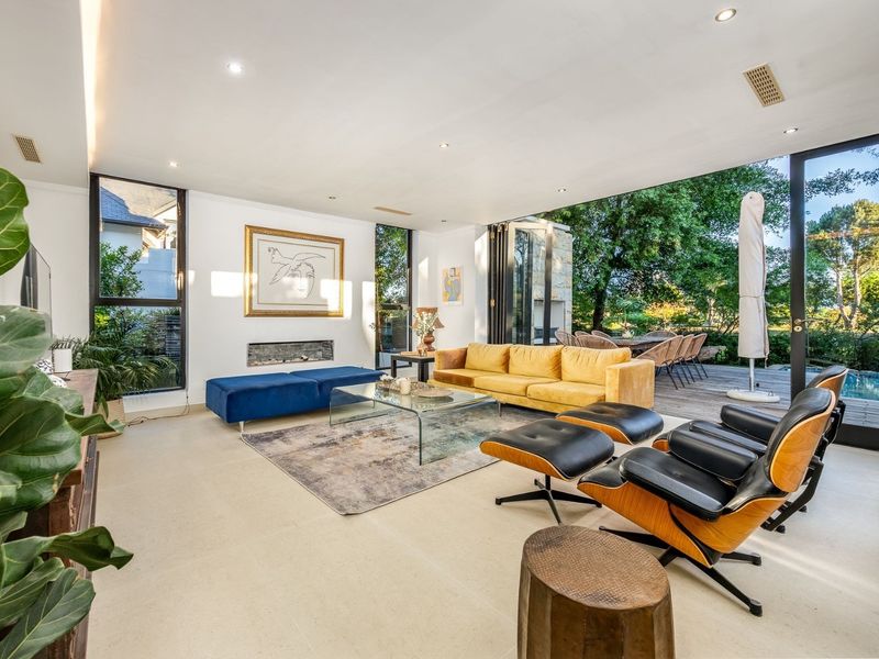 Spacious modern living room featuring a built-in fireplace, recessed lighting, and seamless indoor-outdoor flow through large stacking glass doors to the patio.