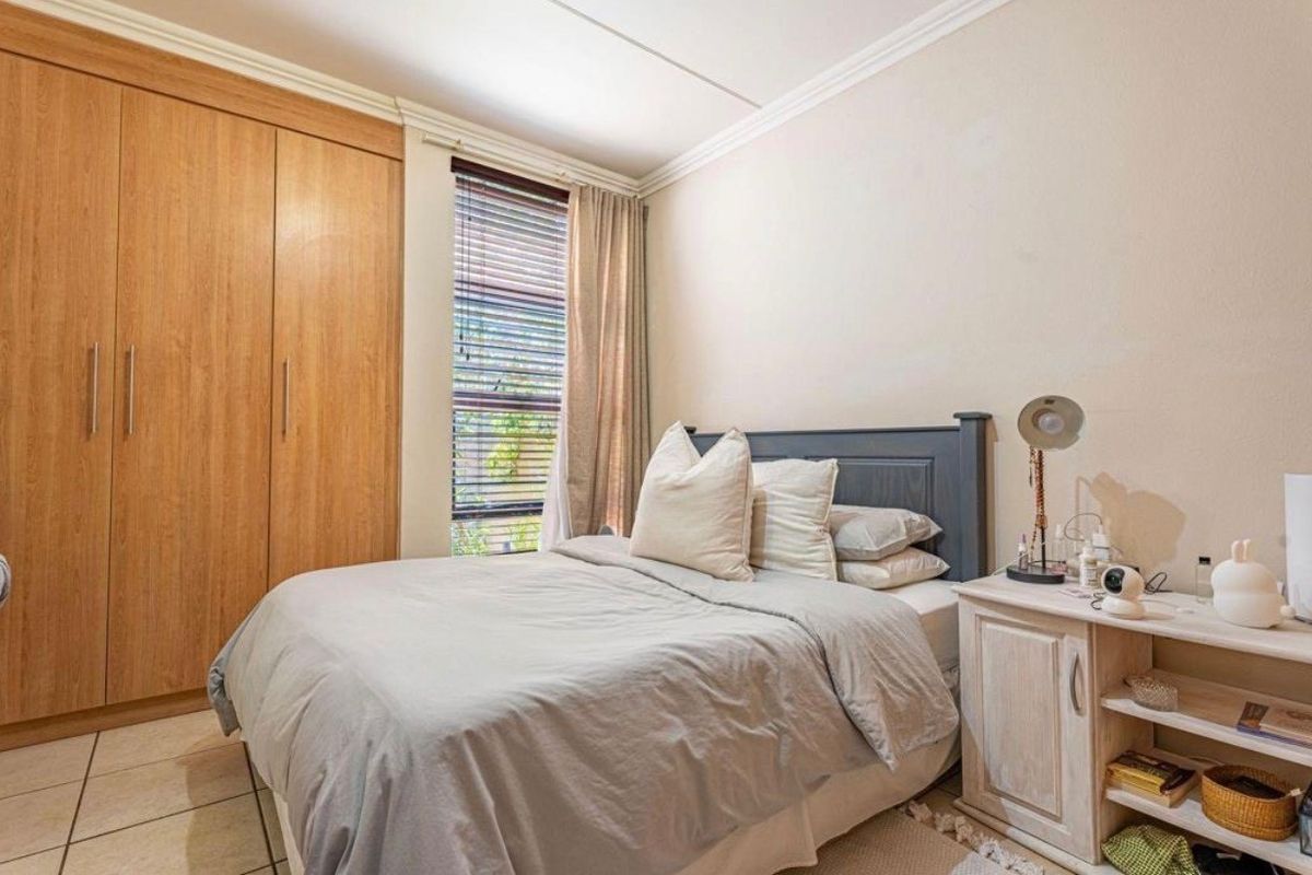 A well-maintained bedroom featuring built-in wooden wardrobes, tiled flooring, and crown molding, providing a functional and comfortable living space.