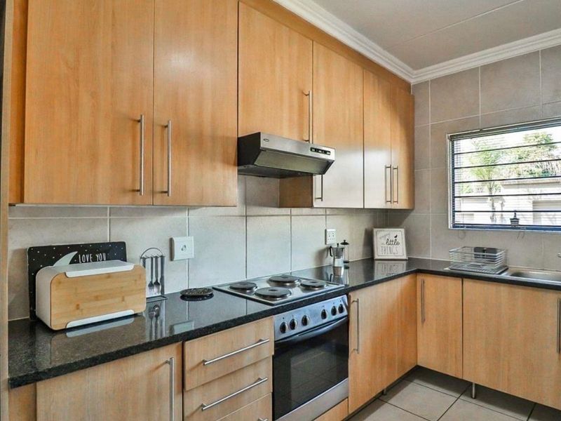 A functional kitchen featuring light wood cabinetry, granite countertops, a built-in electric stove with extractor fan, and a tiled backsplash.