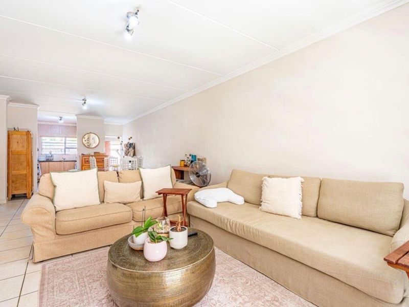 An open-plan living area featuring tiled flooring and neutral walls, seamlessly connecting to the kitchen space in the background.