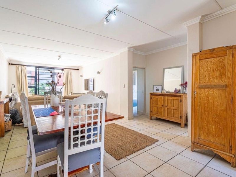 Spacious open-plan living and dining area featuring neutral tiled flooring, coved ceilings, and ample natural light through large windows.