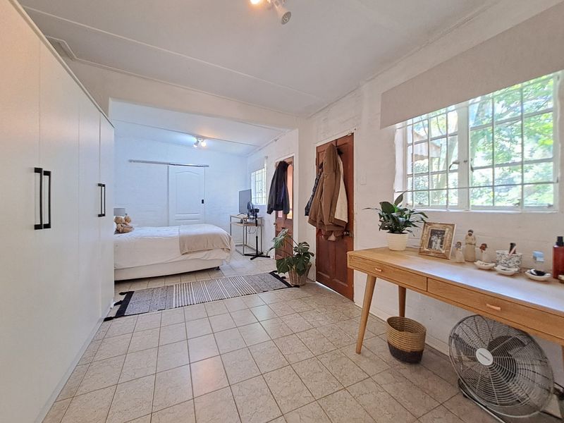 Spacious bedroom featuring tiled flooring, built-in wardrobe storage, and natural light through steel-framed windows.