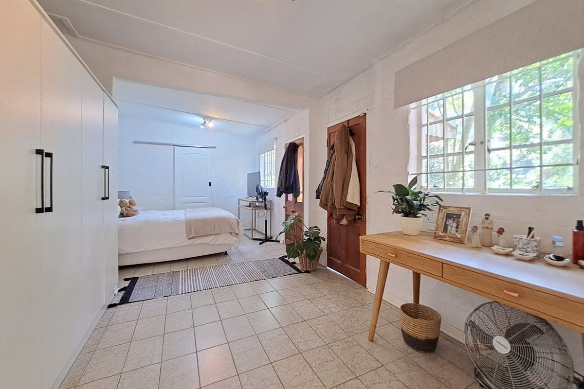 Spacious bedroom featuring tiled flooring, built-in wardrobe storage, and natural light through steel-framed windows.