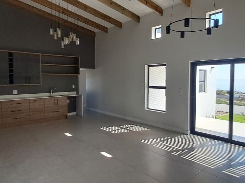Spacious open-plan living area featuring exposed timber beams, modern built-in cabinetry, and large sliding glass doors leading to an outdoor view.