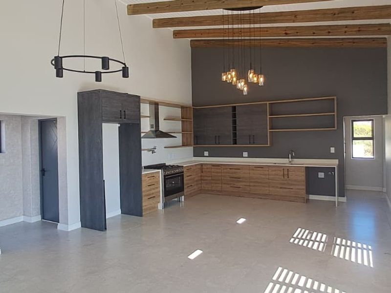 Spacious open-plan kitchen featuring modern cabinetry, exposed timber beams, and high ceilings, creating a bright and airy living environment.
