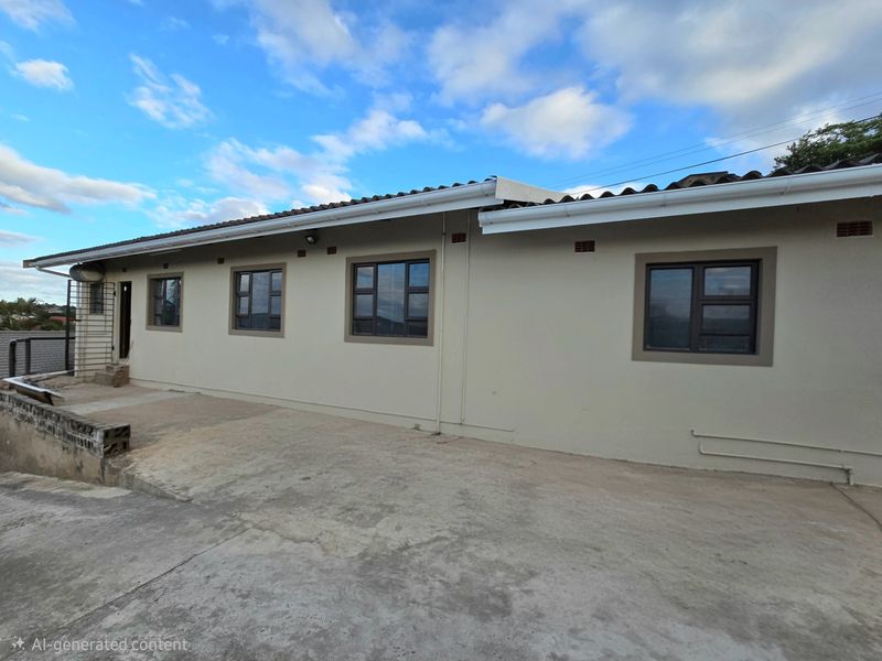 Rear exterior view of the apartment building featuring a concrete apron, tiled roof, and aluminium window frames.