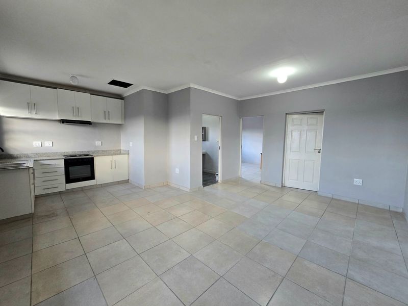 Open-plan living area featuring a functional kitchen with built-in cabinetry, granite countertops, and tiled flooring throughout.