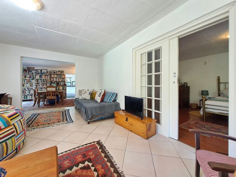 Open plan living area featuring tiled flooring and classic french doors, providing access to adjacent rooms with a view into the dining and bedroom spaces.