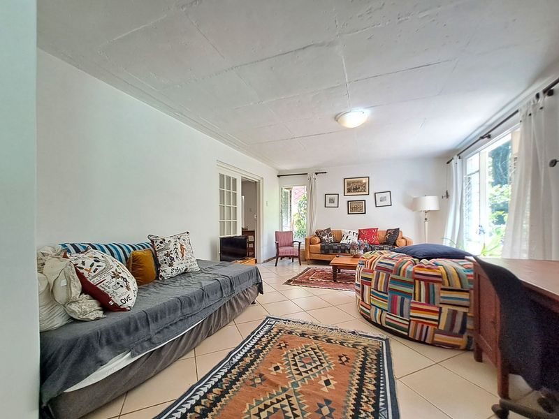 A spacious living room featuring tiled flooring, large windows for natural light, and classic french doors leading to adjacent areas.