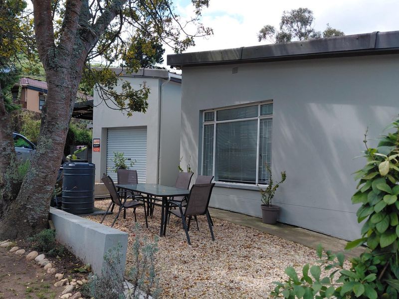Rear exterior view showing a gravel patio area, a single garage with a roller shutter door, and a low retaining wall.