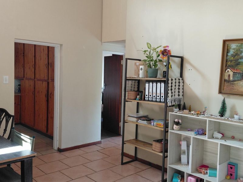 Living area featuring tiled flooring and access to a kitchen with timber cabinetry, showing signs of wear on the walls.