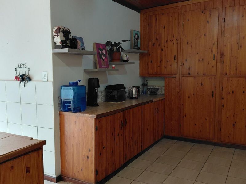 Kitchen area featuring extensive built-in wooden cabinetry, tiled flooring, and a tiled splashback, offering ample storage space with a traditional aesthetic.