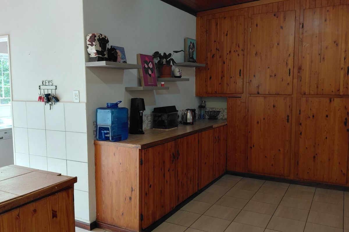 Kitchen area featuring extensive built-in wooden cabinetry, tiled flooring, and a tiled splashback, offering ample storage space with a traditional aesthetic.