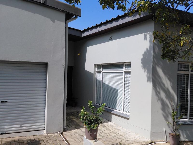 Front elevation of the property featuring a roller garage door, paved entrance area, and neutral painted exterior walls with aluminium window frames.