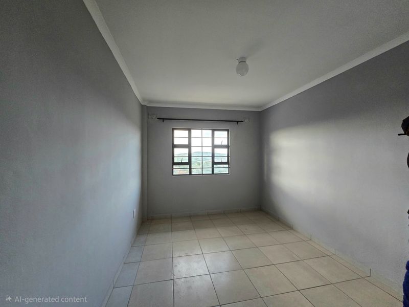 An empty bedroom featuring neutral grey walls, tiled flooring, and a grid-pattern window with a curtain rod.