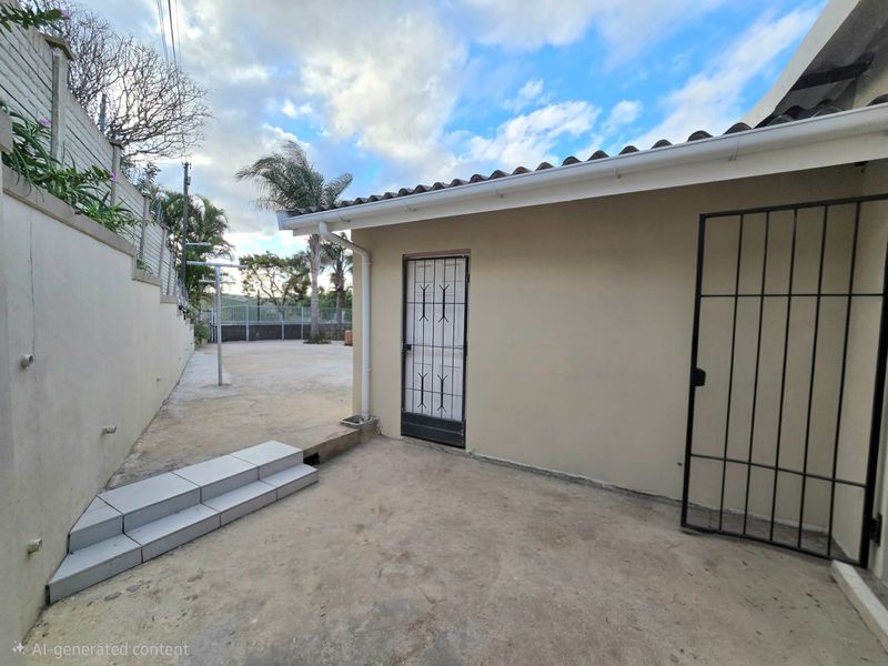 Rear exterior area featuring concrete paving, a security gate, and tiled steps leading to a retaining wall.