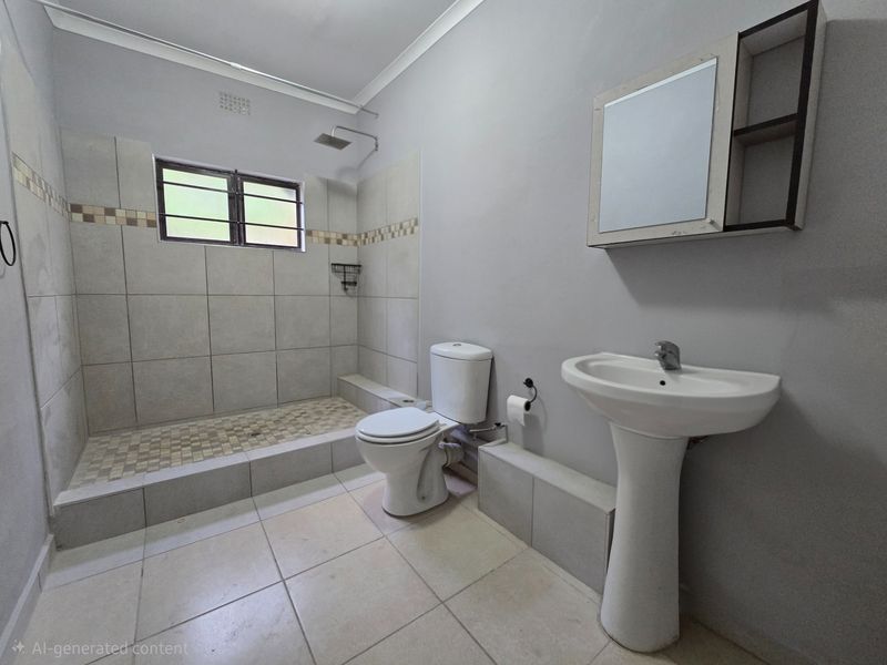 A functional bathroom featuring a walk-in shower with tiled surround, a pedestal basin, and a standard toilet.